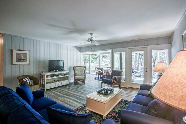 A living room with a television, wicker chairs, a sofa, and a coffee table.