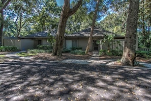 A two-story house with a front yard, surrounded by trees.