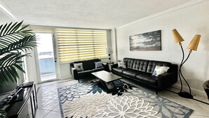 Ein Wohnzimmer mit einer schwarzen Ledersofa, einem Couchtisch und einem gemusterten Teppich.