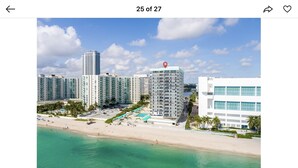 Ein Küstenhotel mit mehreren Hochhäusern, einem Strand und einem Poolbereich.