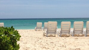 A beach with rows of white lounge chairs facing the ocean. - Oceanfront 2Bd/2Ba Penthouse Condo  (Bavaro)