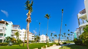 A resort with a pathway, palm trees, and buildings with balconies. - Oceanfront 2Bd/2Ba Penthouse Condo  (Bavaro)