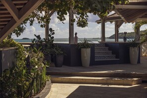 A covered outdoor area with a view of the sea, featuring a tiled staircase and potted plants.