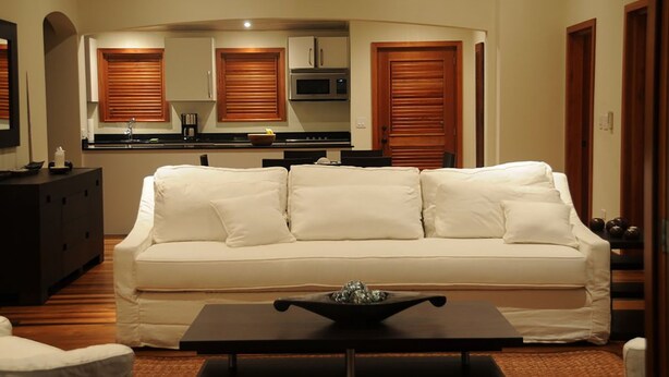 Una sala de estar con un sofá blanco, una mesa de centro y una cocina al fondo.