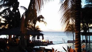 A beachside restaurant with outdoor seating, palm trees, and a view of the ocean. - INFINITY BAY VACATION SALE! ULTRA Low Rates for our Low Season Dates! (West Bay Beach)