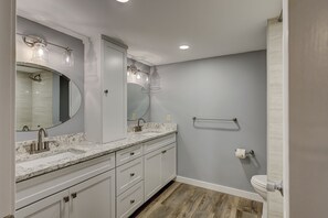 Un baño moderno con lavamanos doble, un espejo grande, ducha y retrete.