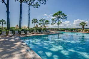 Una piscina con sillas de descanso y palmeras.