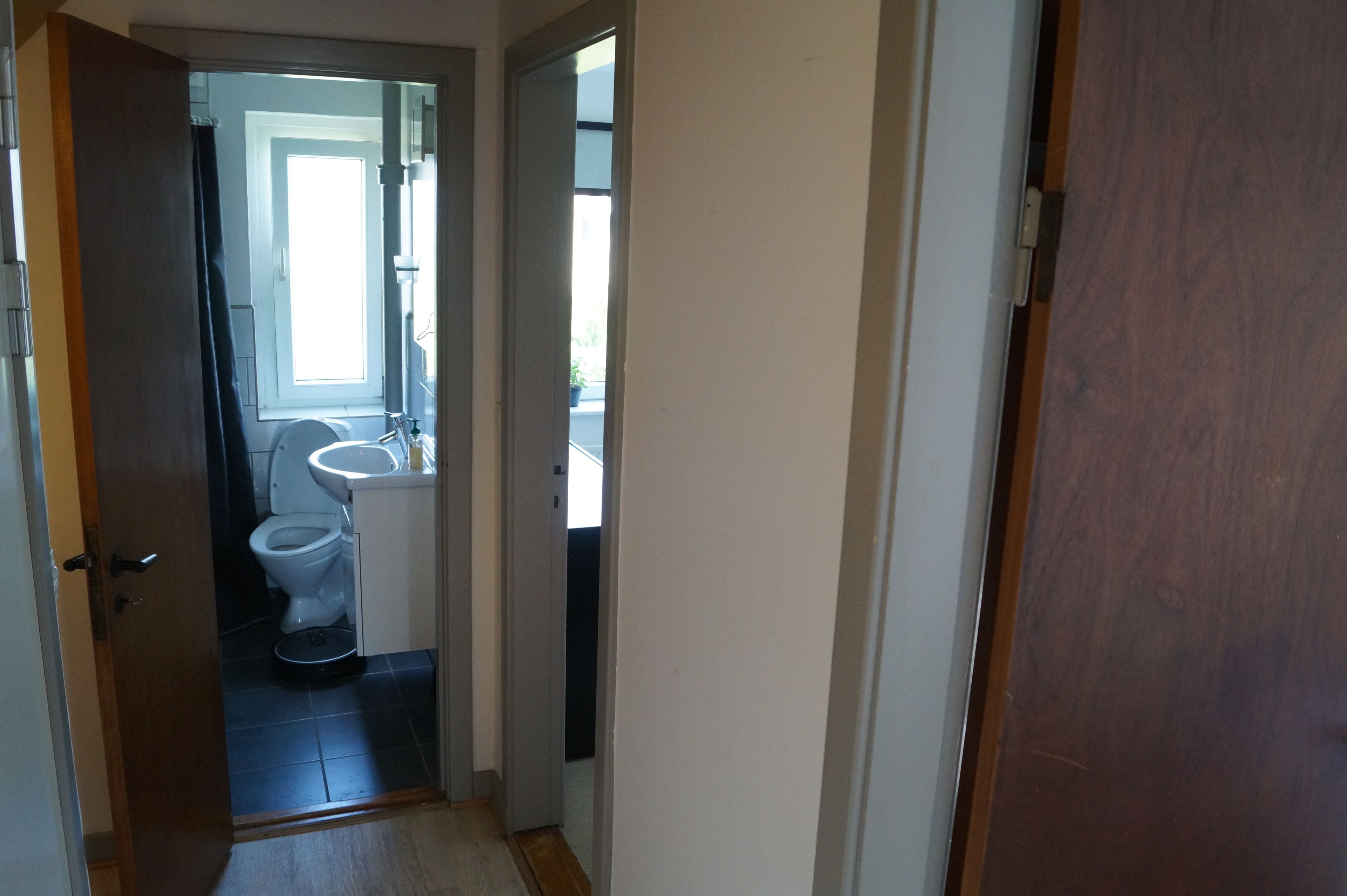 Un pasillo estrecho que conduce a un baño con inodoro y lavamanos.