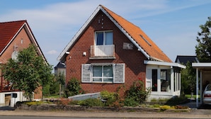 Ein zweistöckiges Backsteinhhaus mit rotem Ziegeldach, einem Balkon und einer Garage.