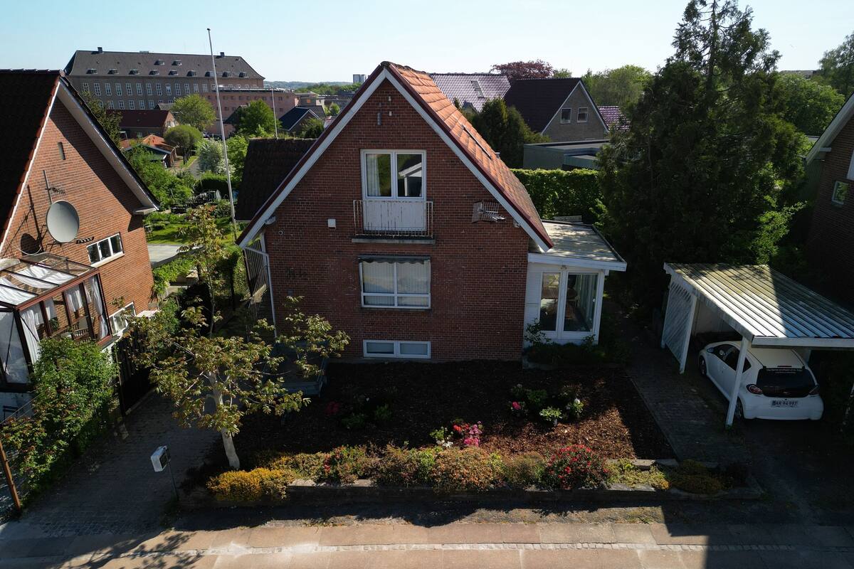 Ett tvåvåningshus med ett sluttande tak, en satellitantenn och ett garage.