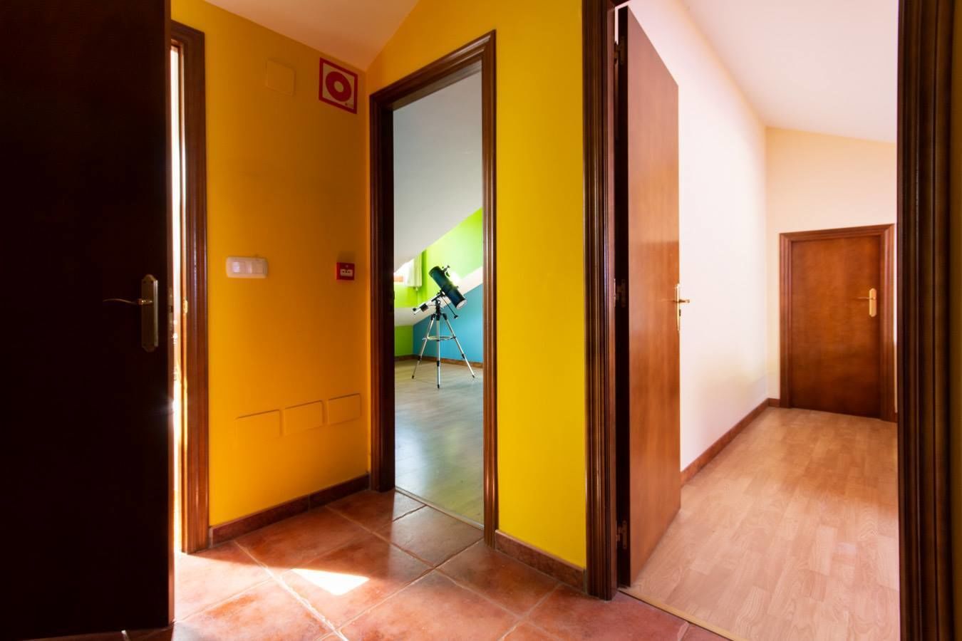 Un passadís amb parets grogues i una porta de fusta.