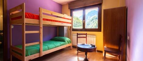 A bunk bed room with a window, a radiator, and a wooden chair.