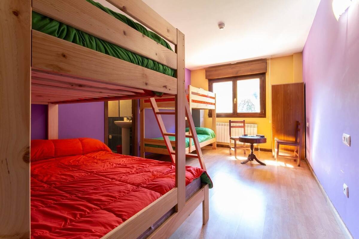 Une chambre avec des lits superposés, une petite table et une fenêtre.