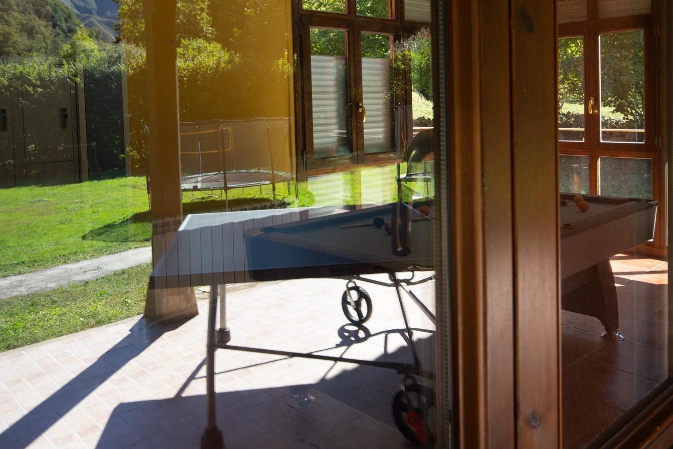 Una mesa de billar con vistas despejadas del entorno, que incluyen un césped y una terraza de madera.