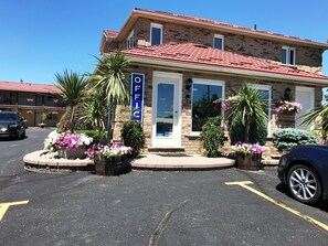 A two-story building with a red-tiled roof, a sign reading "OFFICE," and a parking lot with yellow lines.