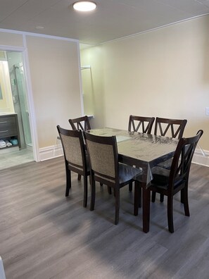 A dining area with a rectangular table and six chairs, a glass partition, and a wooden floor.