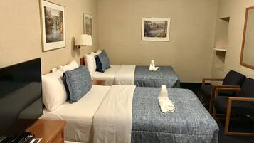 A hotel room with two beds, a desk with a TV, and a chair.