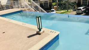 A swimming pool with a 3FT depth marker, a metal railing, and a staircase leading to a building. - Modern Comfort Suites (Kingston)