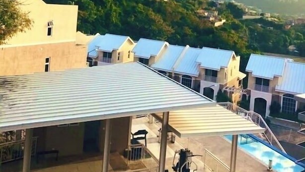 A hotel with a pool, multiple buildings, and a mountainous backdrop. - Modern Comfort Suites (Kingston)