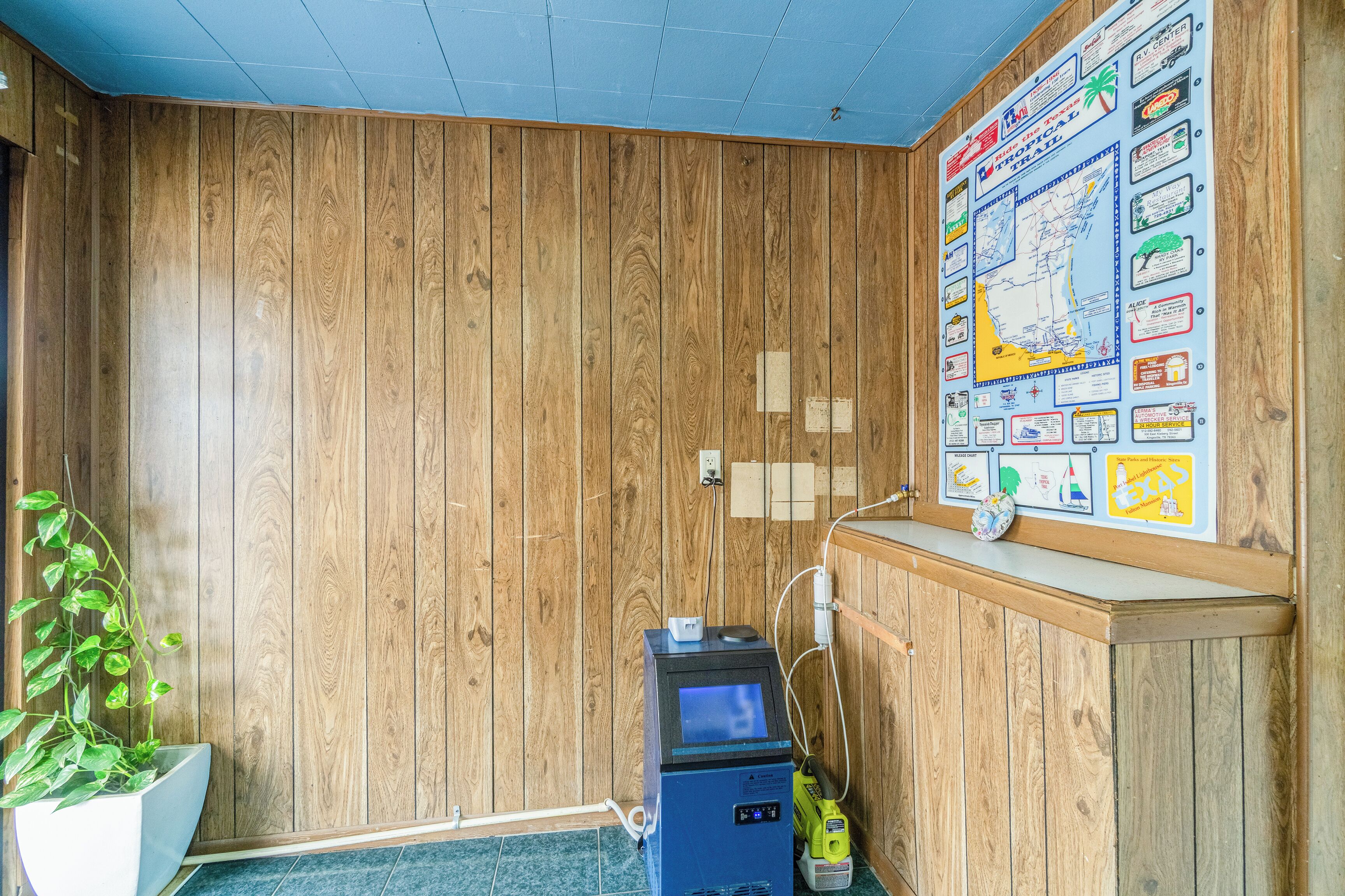 A room with wooden walls, a map on the wall, a desk, and a plant.