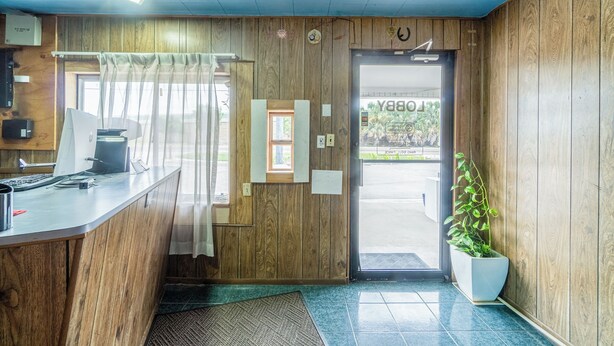 A reception desk with a computer, a small window, and a potted plant. - OYO Budget Inn Falfurrias Hwy 281 (Falfurrias)
