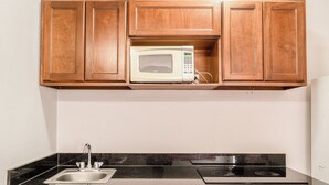 A kitchen with wooden cabinets, a microwave, a sink, and a stove. - OYO Budget Inn Falfurrias Hwy 281 (Falfurrias)