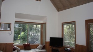 A spacious room with large windows, a ceiling fan, and a television.