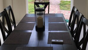 A dining table with a remote control, black chairs, and a candle centerpiece. - Luquillo Beach- Puerto Rico, 4 Bedroom Vacation Villa With Pool and Wifi (Luquillo)