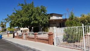 A residential property with a gated entrance, a brick wall, and a tree in front. - STATE/CITY LICENSED AND PERMITTED! 3 bed 2 bath Single Family Home Pet Friendly. (Las Vegas)