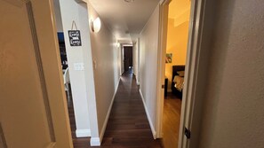 A hallway with a wooden floor, a light switch, and a sign that says 'home sweet home.'