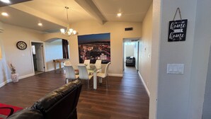 A spacious living area with a dining table, chairs, a sofa, and a cityscape mural. - STATE/CITY LICENSED AND PERMITTED! 3 bed 2 bath Single Family Home Pet Friendly. (Las Vegas)