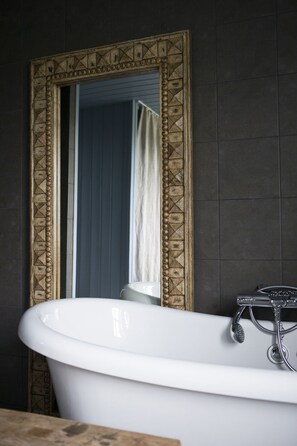 Un baño con una bañera blanca, un espejo con marco decorativo y una cortina de ducha.
