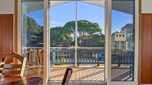 Une pièce dotée d’une grande porte-fenêtre coulissante qui donne sur une terrasse extérieure offrant une vue sur les arbres.