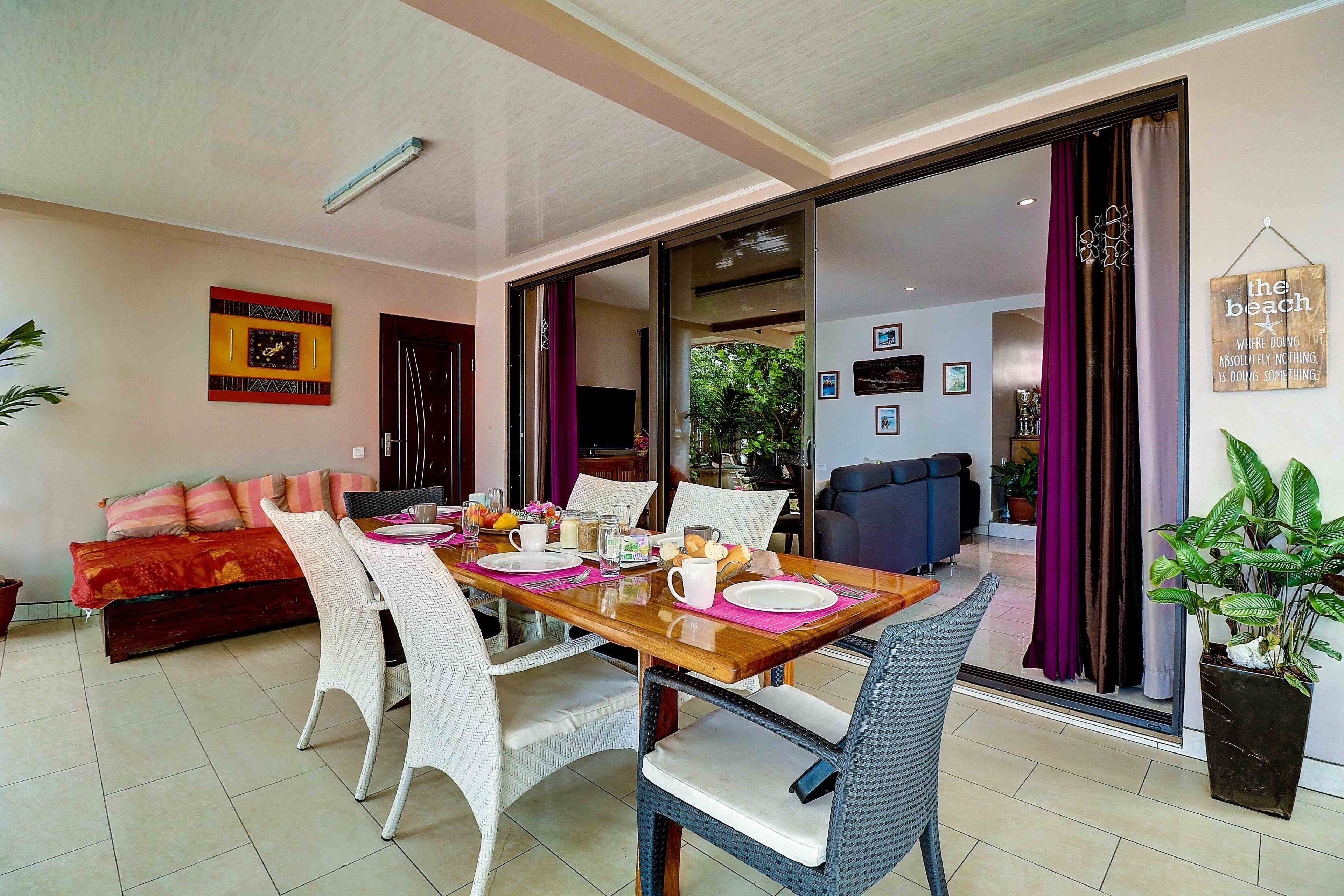 A dining area with a wooden table set for four, surrounded by wicker chairs.