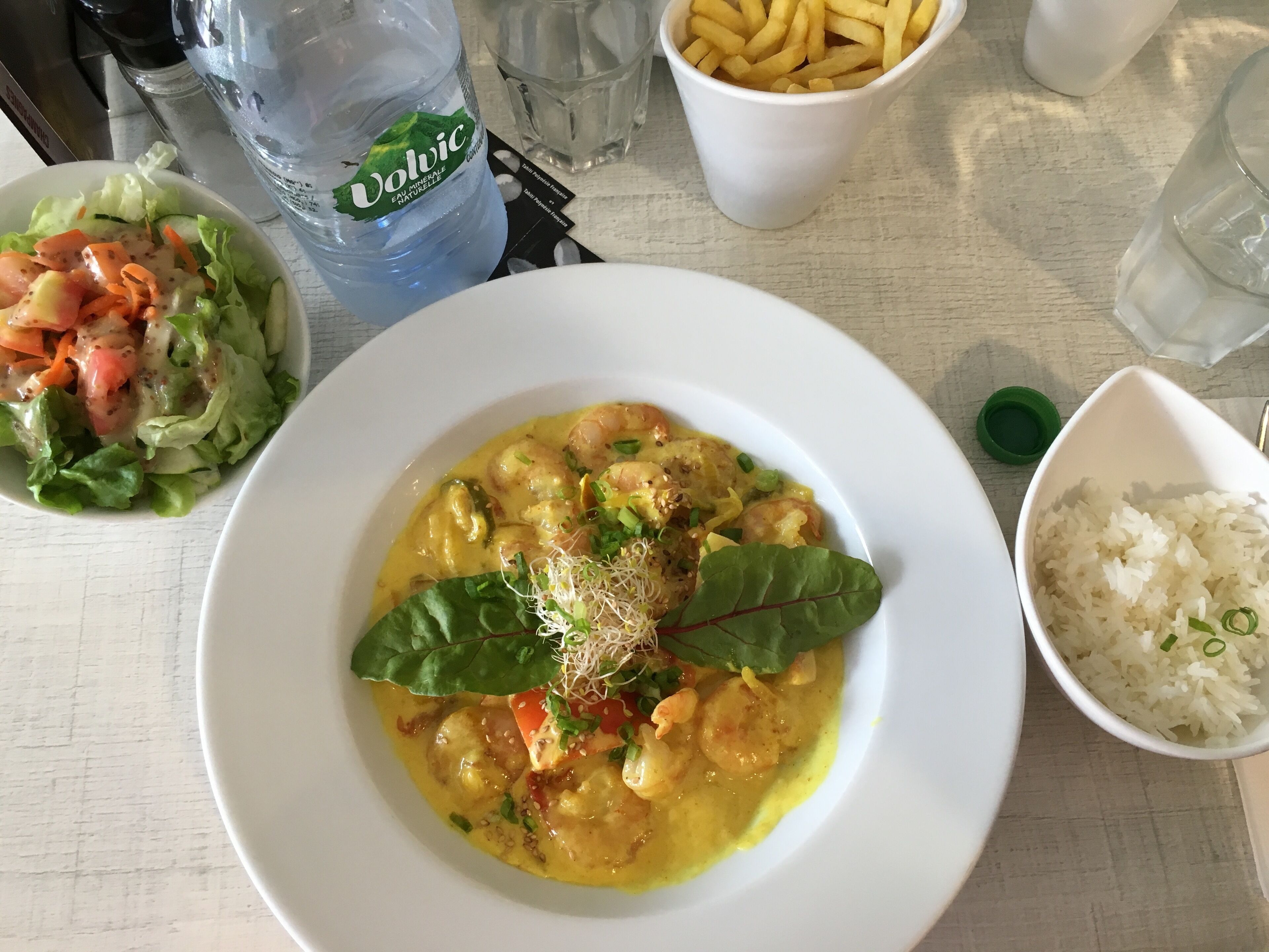 Un repas composé de curry de crevettes, de riz, de frites et d’une salade.
