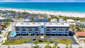 Een meerhoog hotel met zwembad, nabij een strand en een parkeerplaats.
