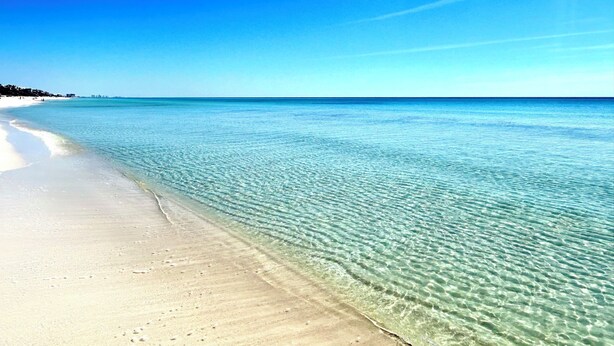 Een strand met helder ondiep water en een zandkust.