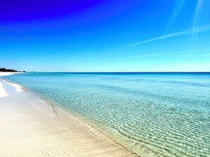 Een strand met helder ondiep water en een zandkust.