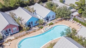 Une piscine entourée de maisons, avec une terrasse couverte.