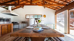 A spacious kitchen with a large wooden table set for dining, a built-in oven, and a refrigerator. - Place with complete leisure 100km from São Paulo (Porto feliz)