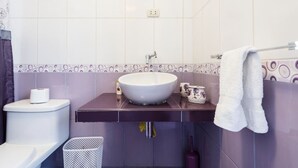 A bathroom with a white toilet, a white sink, and a purple vanity.