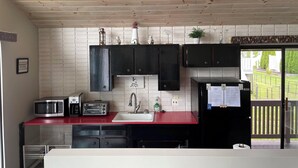 A compact kitchen with wooden ceiling, black cabinets, a red countertop, a sink, a microwave, a toaster, and a refrigerator. - The San'Bar - Great Family Home Just A Short Walk To York's Beautiful Beaches (York)