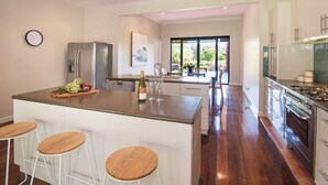 A modern kitchen with a central island, bar stools, stainless steel appliances, and a large window providing natural light.