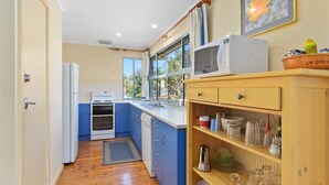 A compact kitchen with a stove, oven, microwave, and a sink. - 22 Broadbeach Drive Carrickalinga (CARRICKALINGA)