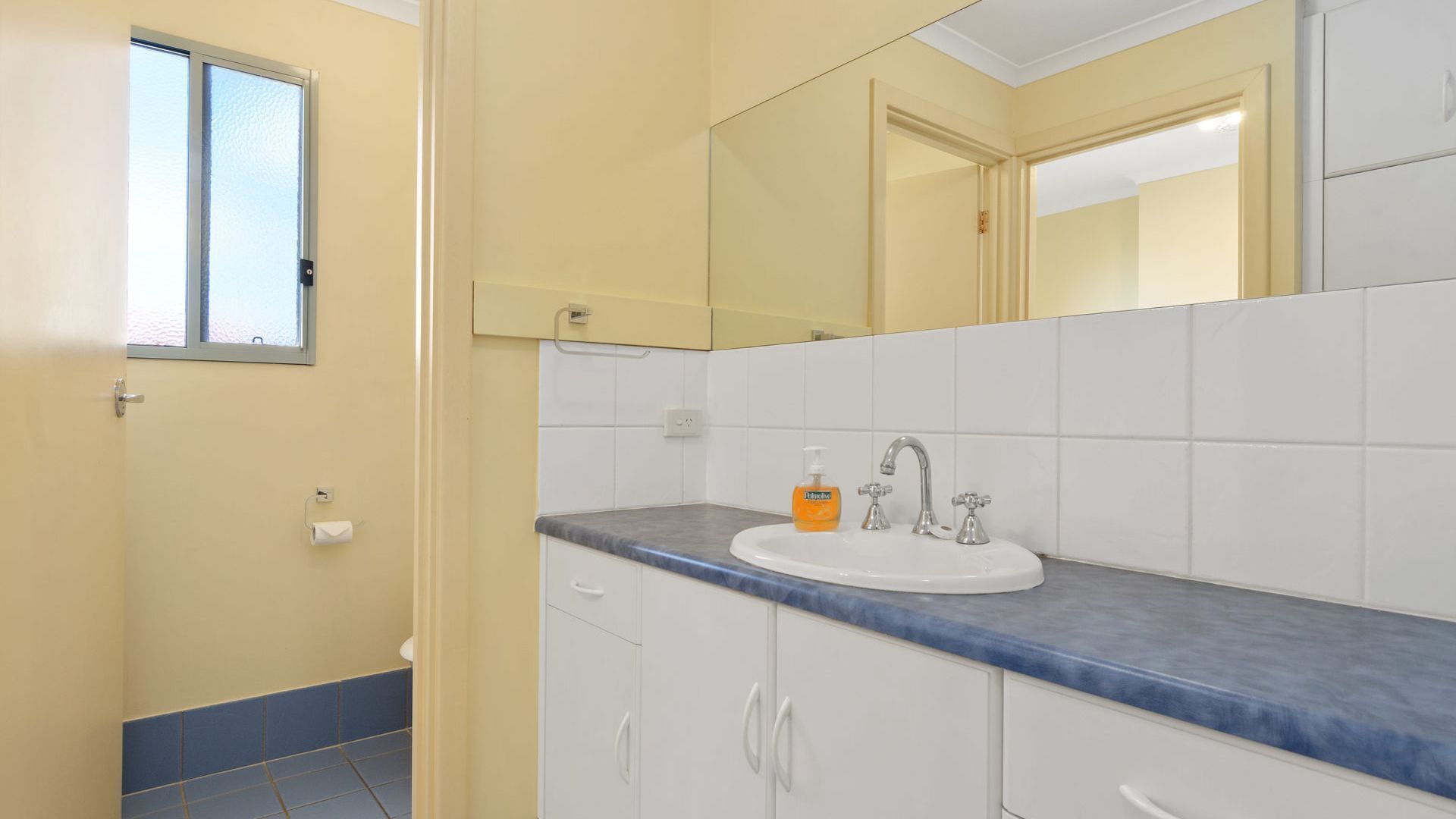 A bathroom with a white sink, a mirror, and a window.