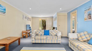 A cozy living room with a plaid sofa, a wooden coffee table, and a bookshelf. - 22 Broadbeach Drive Carrickalinga (CARRICKALINGA)