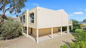 A modern two-story house with a flat roof, large windows, and a covered outdoor area. - 22 Broadbeach Drive Carrickalinga (CARRICKALINGA)
