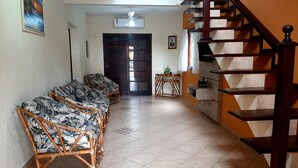 A living room with a sofa set, a staircase, and a door leading to another room. - Beautiful house with pool and great location (Caraguatatuba)