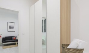 Ein modernes, minimalistisches Zimmer mit einer Schiebetür, einer Couch mit Kissen, einem Korbwäsches mit Kissen und einem gerahmten Bild an der Wand.