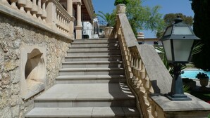Eine Steintreppe mit aufwendiger Balustrade führt zu einem Hauseingang.